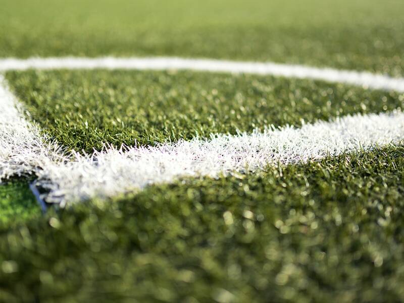 Die Ecke des Fußballplatzes, grünes Gras und weiße Linien.