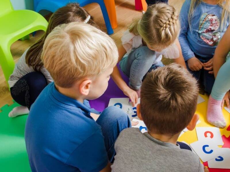 Hier ist einen Frau zu sehen, die mit Kindern spielt. Der lickwinkel istvon obn auf sie und spielende Kinder.