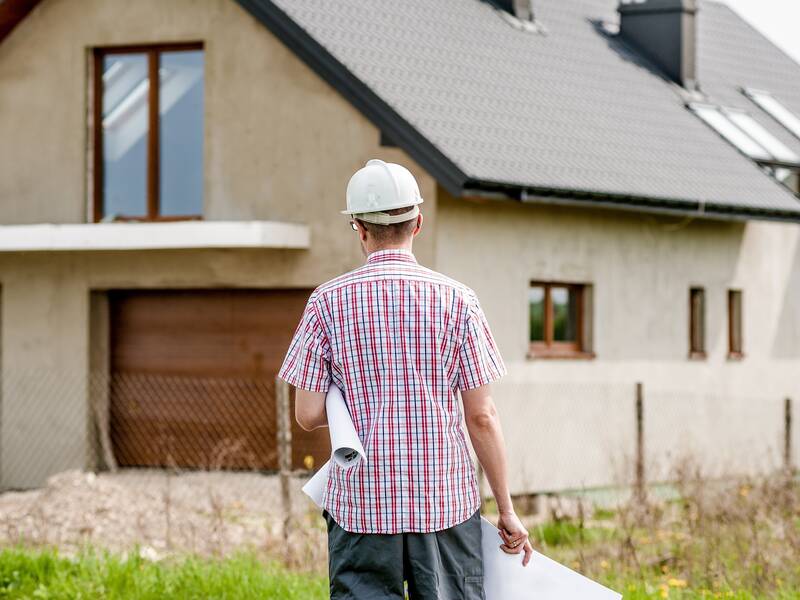Architekt mit Bauhelm vor einem Neubau