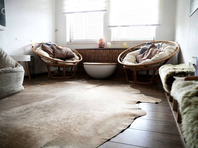 Jugendhaus. Ein gemütlich eingerichteter Raum mit zwei runden Rattansesseln, einem zentralen kleinen Tisch und einem hellen Teppich auf einem Holzboden.