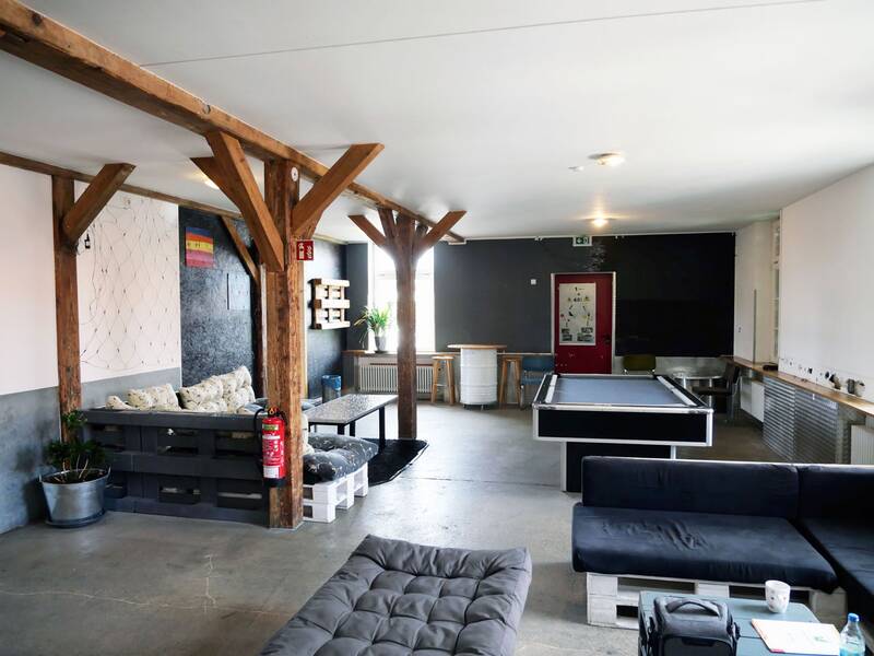 Jugendhaus. Ein heller Raum mit Holzbalken, in dem sich ein Billardtisch, Sofas aus Paletten und moderne Dekorationen befinden.