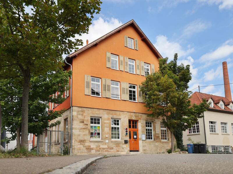 Das Metzinger Jugendhaus. Ein rot-oranges Gebäude mit 4 Stockwerken und einer roten Tür.