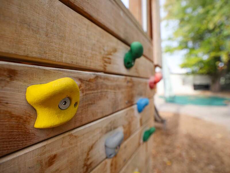 Nahaufnahme einer Kletterwand aus Holz mit bunten Klettergriffen.