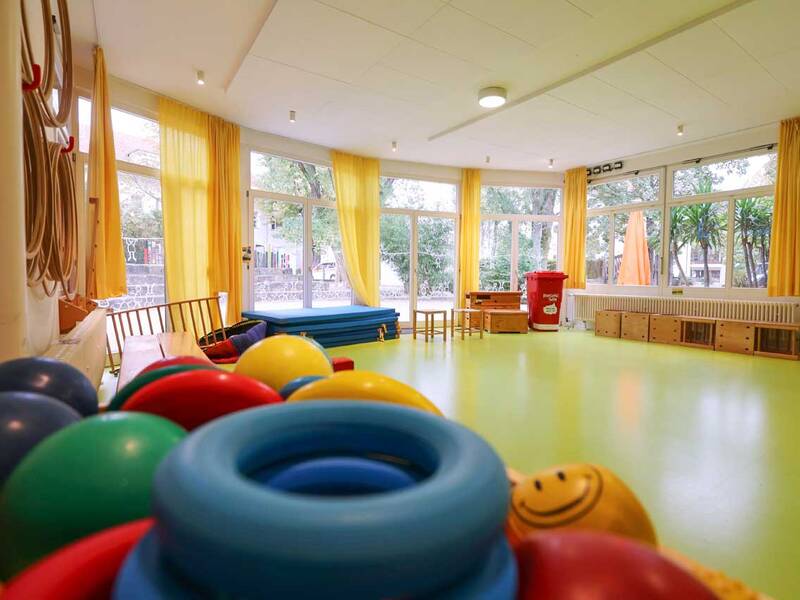 Bewegungsraum: Innenraum mit bunten Bällen, Matten und Ringen.