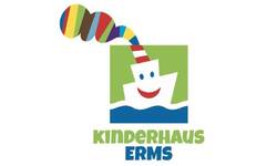 Das Bild zeigt ein Logo mit einem stilisierten, weißen Boot mit Gesicht, aus dessen Schornstein bunte Streifen herauskommen, und darunter steht in grüner und blauer Schrift "Kinderhaus Erms".