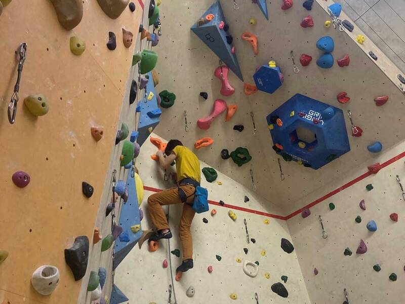 Kletterer an einer Boulderwand, vom Boden aus betrachtet.