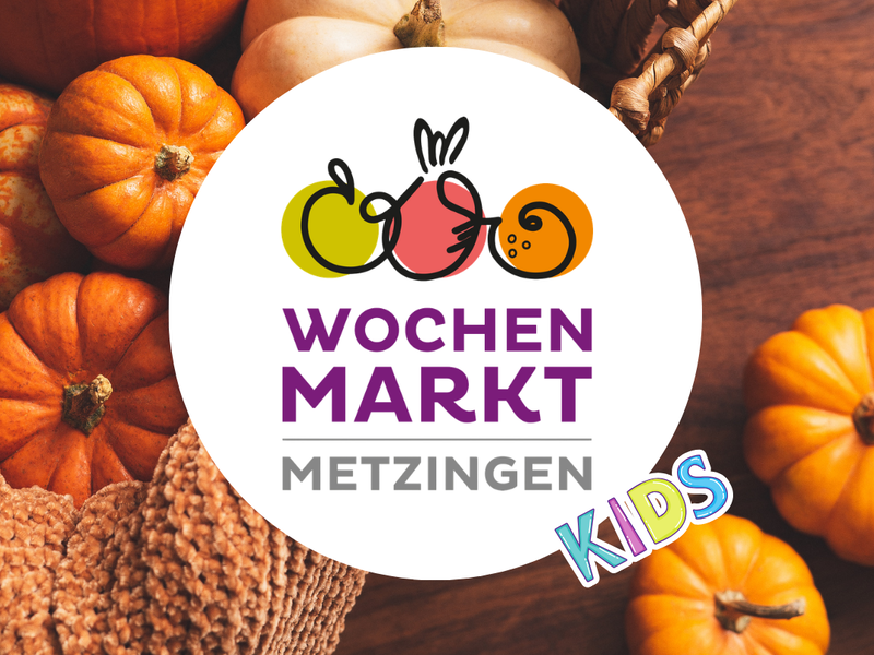 Das Bild zeigt bunte Kürbisse neben einem Werbeplakat für den Herbstzauber auf dem Wochenmarkt Metzingen.
