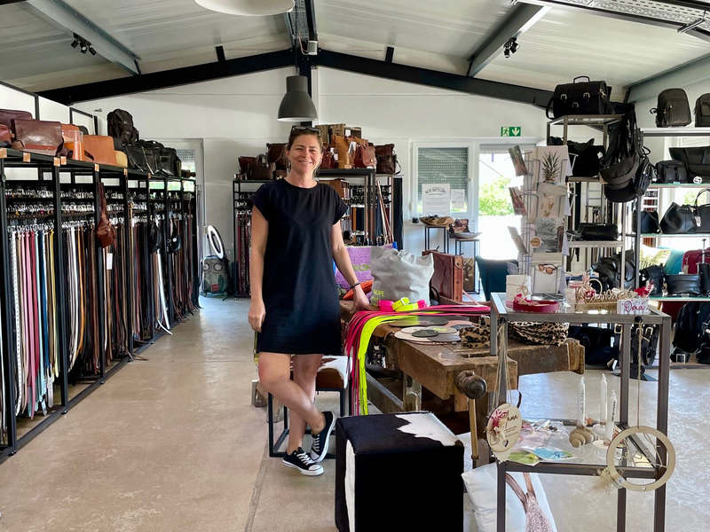 Eine Frau steht in einem modernen Geschäft mit Regalen voller Taschen und Accessoires.